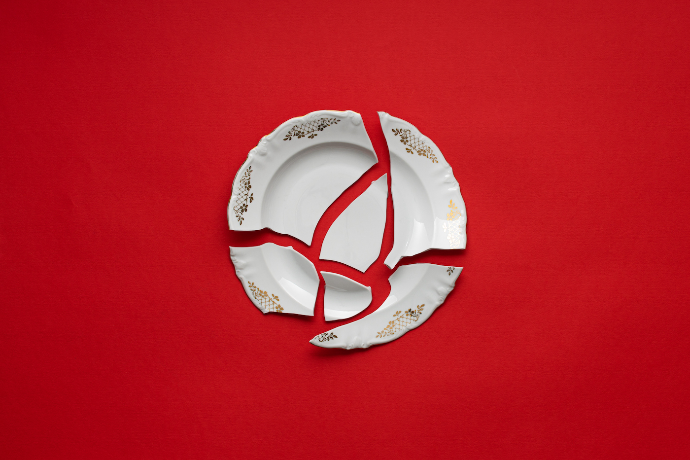 Broken white plate on red background