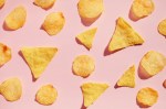 Potato chips pattern over pink background, hard light with shadows. Unhealthy junk food concept.