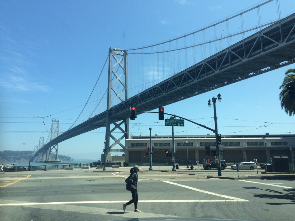 Woman Walking On Street Against Bay Bridge