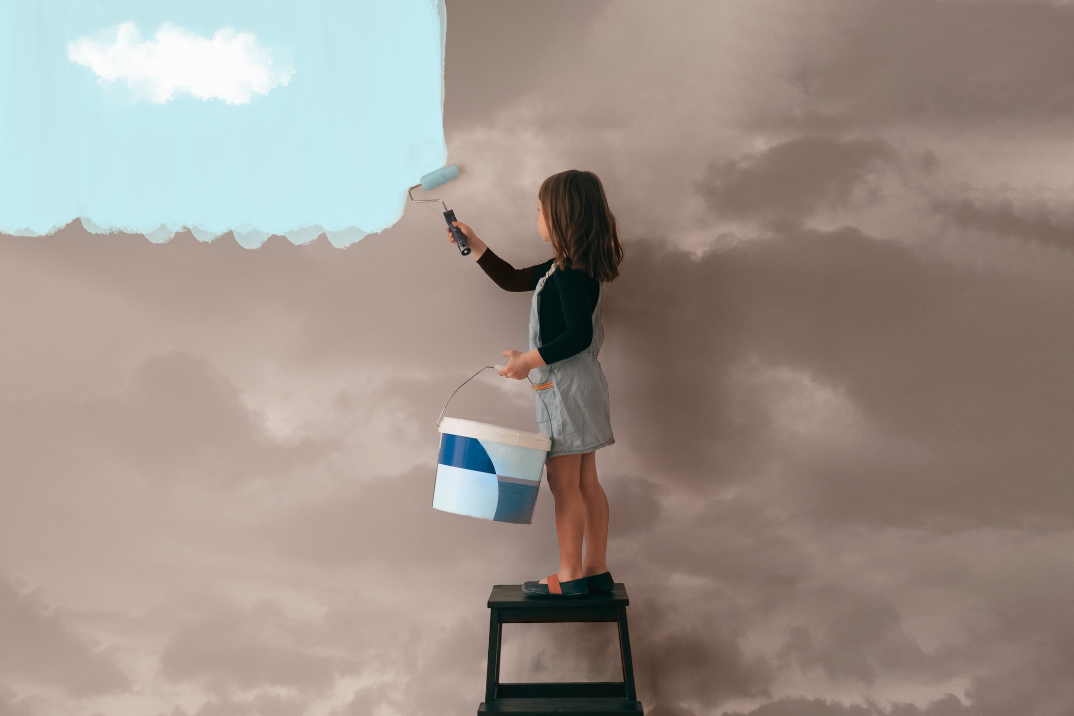 A girl painting a wall against a cloudy to clear blue sky.Cloud optimization