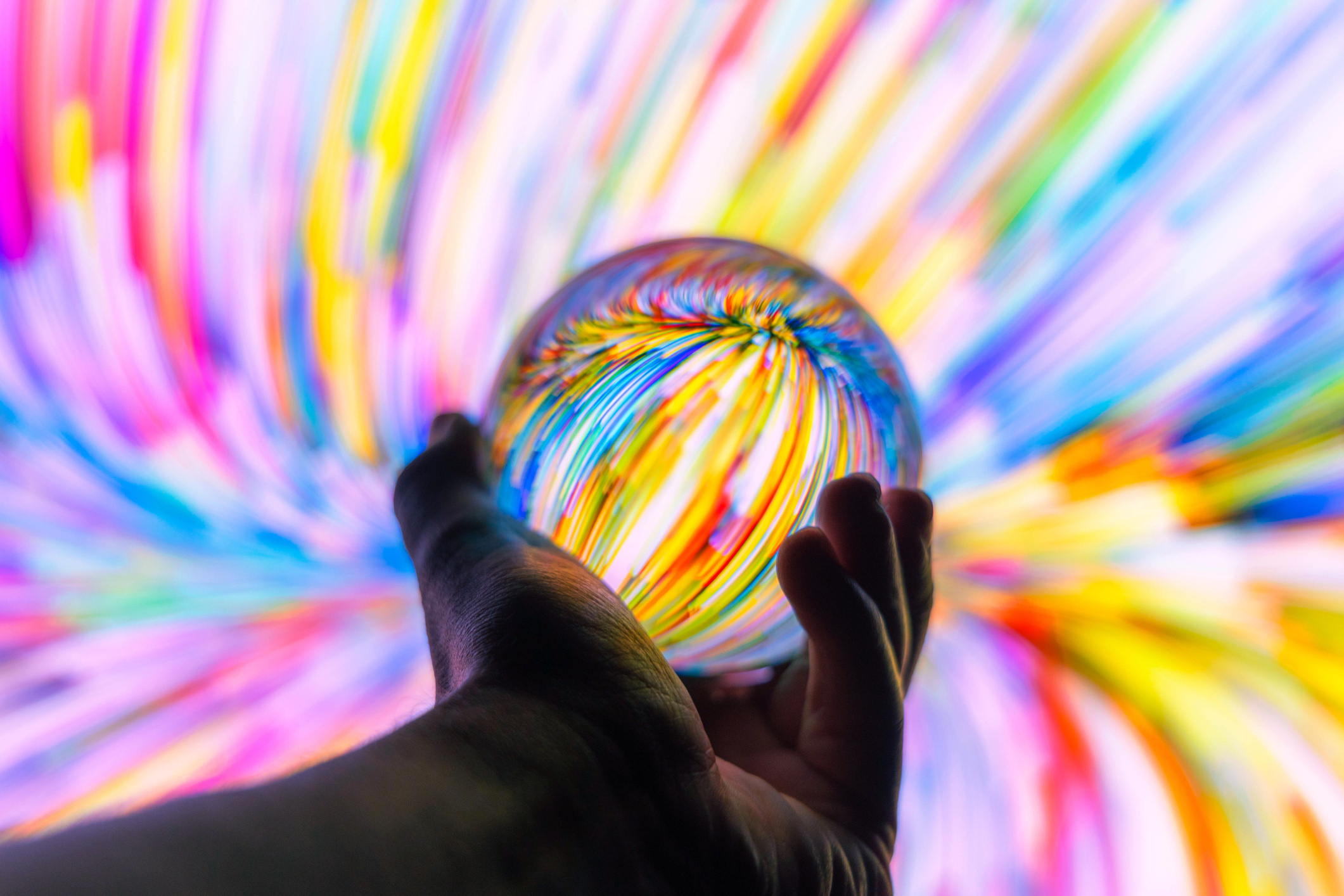 Holding a crystal ball through colorful background at night.