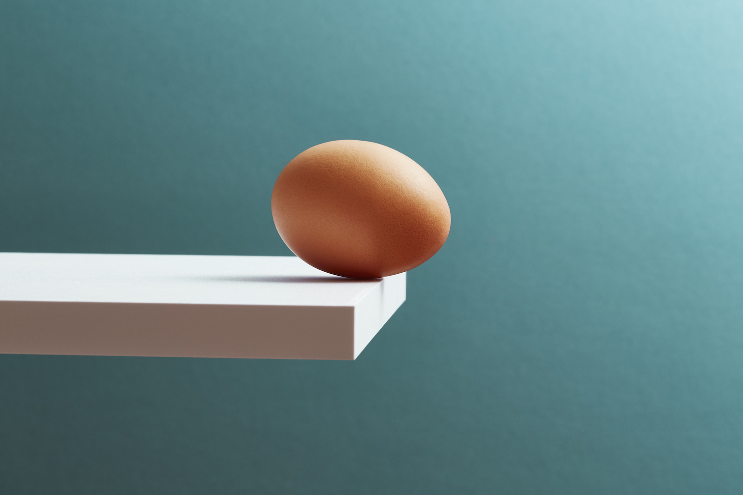 An egg teetering on the edge of a plank