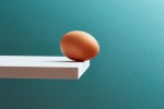 An egg teetering on the edge of a plank