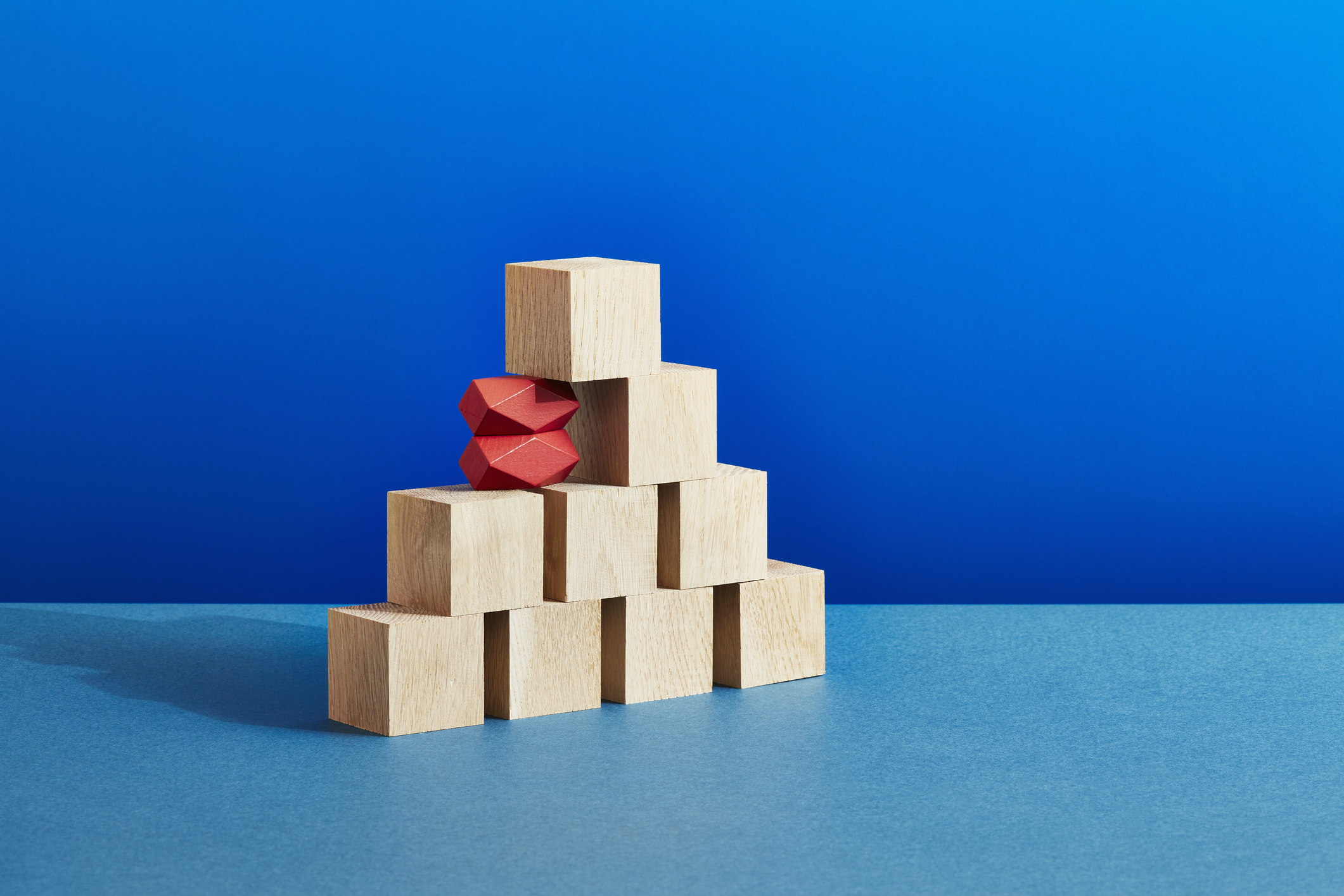 A stack of plain wooden blocks with two unusual red blocks supporting the edge
