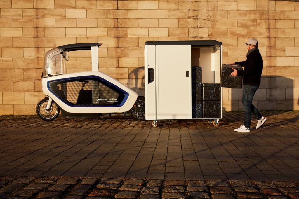 Onomotion e cargo bike and container viewed from the side as a man loads a parcel