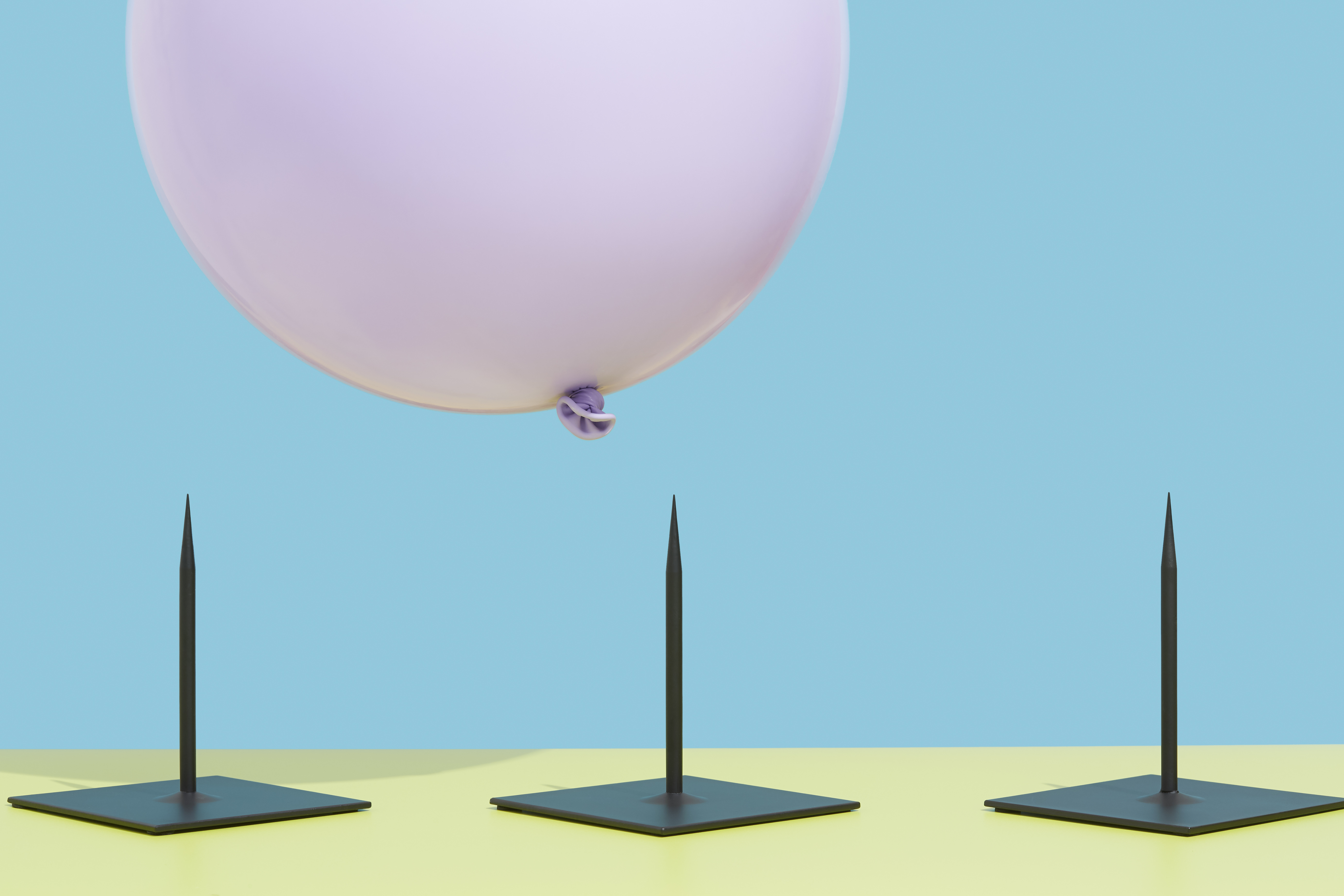 Picture of pink balloon hovering over three nails to represent risk.