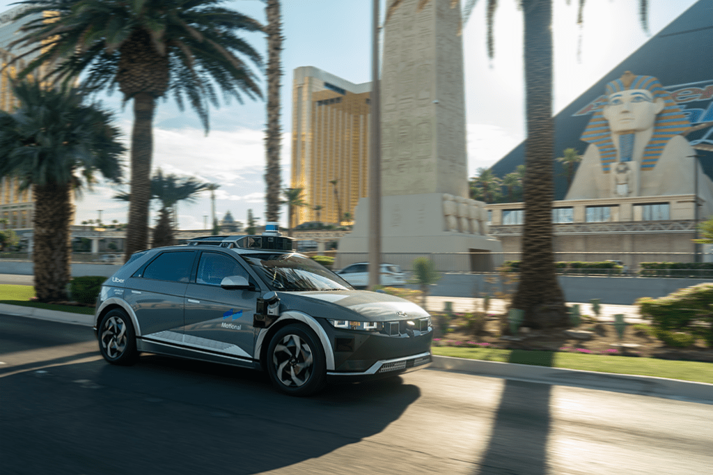 A Motional ioniq 5 robotaxi with Uber branding on street with palm trees