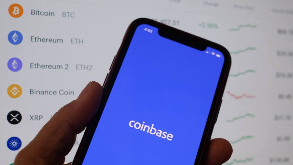 Coinbase's logo on a phone in front of crypto prices