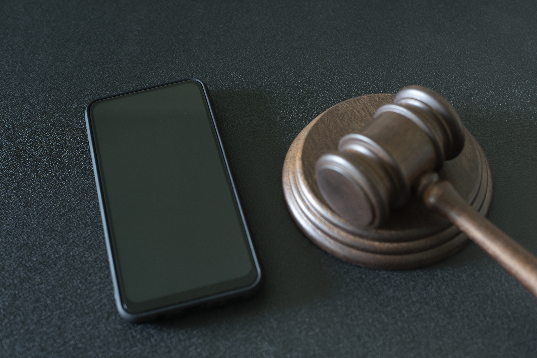 Smartphone y mazo de juez sobre fondo negro
