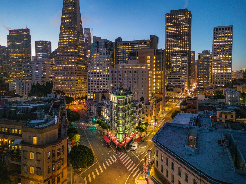 An aerial view at sunrise looking at Columbus Ave in San Francisco with iconic buildings on the horizon.