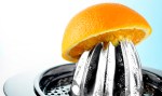 half of an orange balanced atop a metal juicer