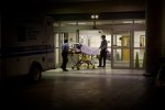a person wheeled in on an ambulance stretcher outside of a U.S. emergency room at night