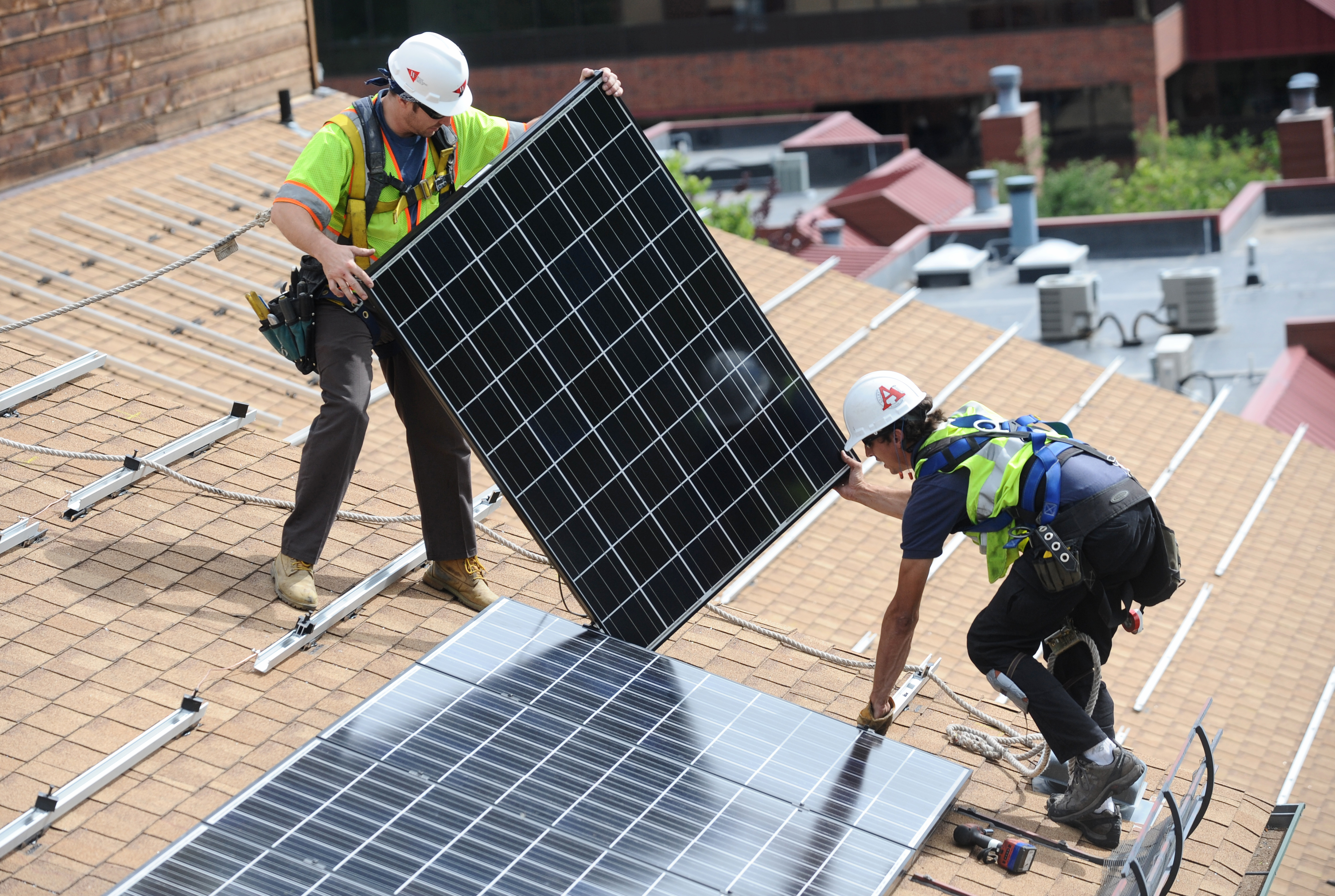 Crew installs solar panels on an apartment complex.