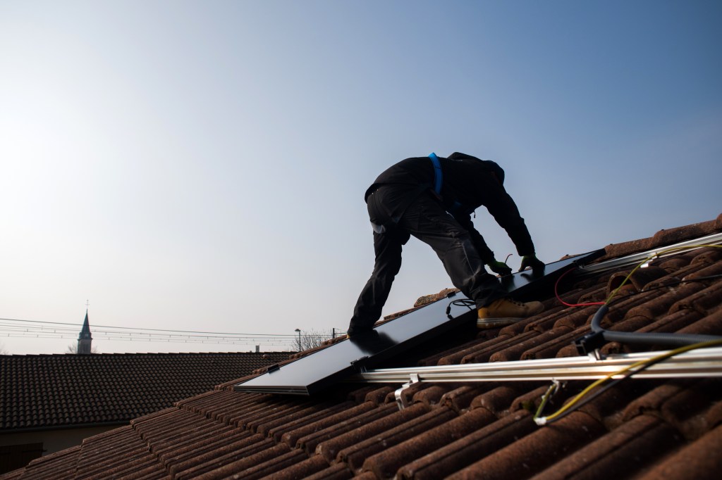 Man on a roof, installing solar panels