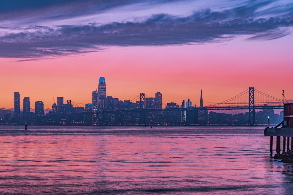 A scenic purple sunset with Oakland Bay Bridge in San Francisco with skyscrapers in the background