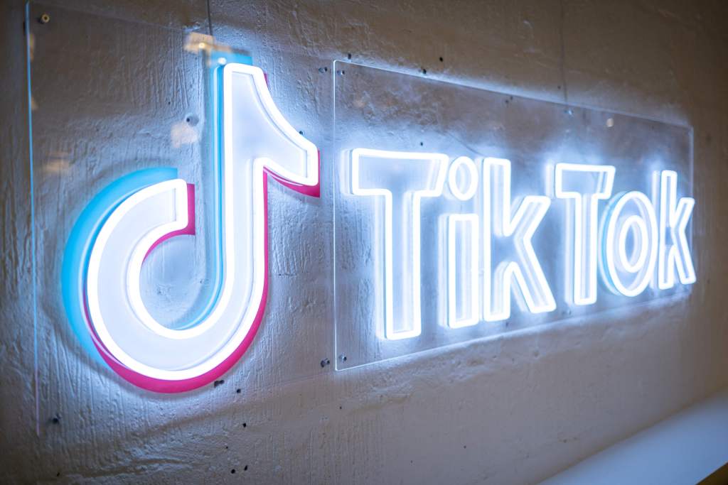 TikTok's neon logo and music note symbol on a concrete wall