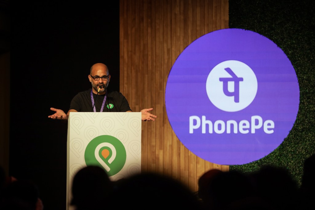 Man speaking at a podium with PhonePe logo displayed to side