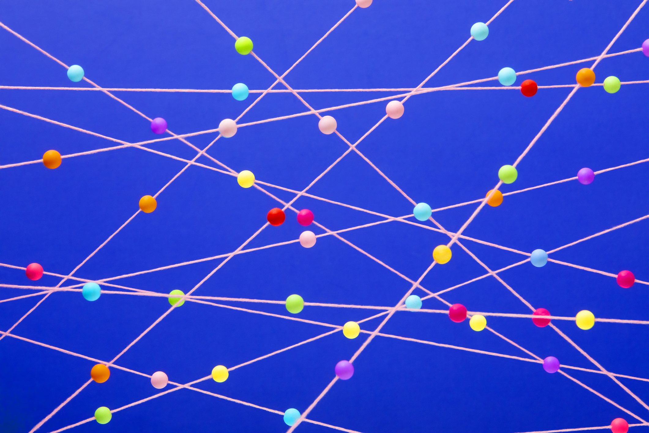 Bright multi-colored balls randomly arranged on pink strings on a blue background, used in post about beterdata