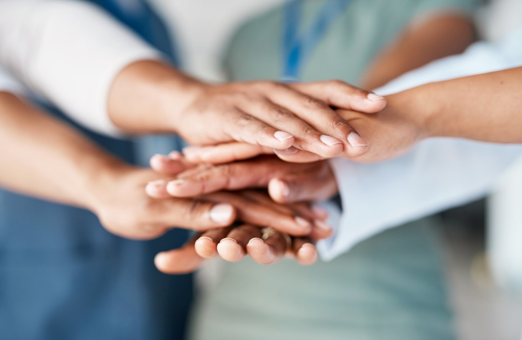 Hands together showing a group of people joining together to help one another.