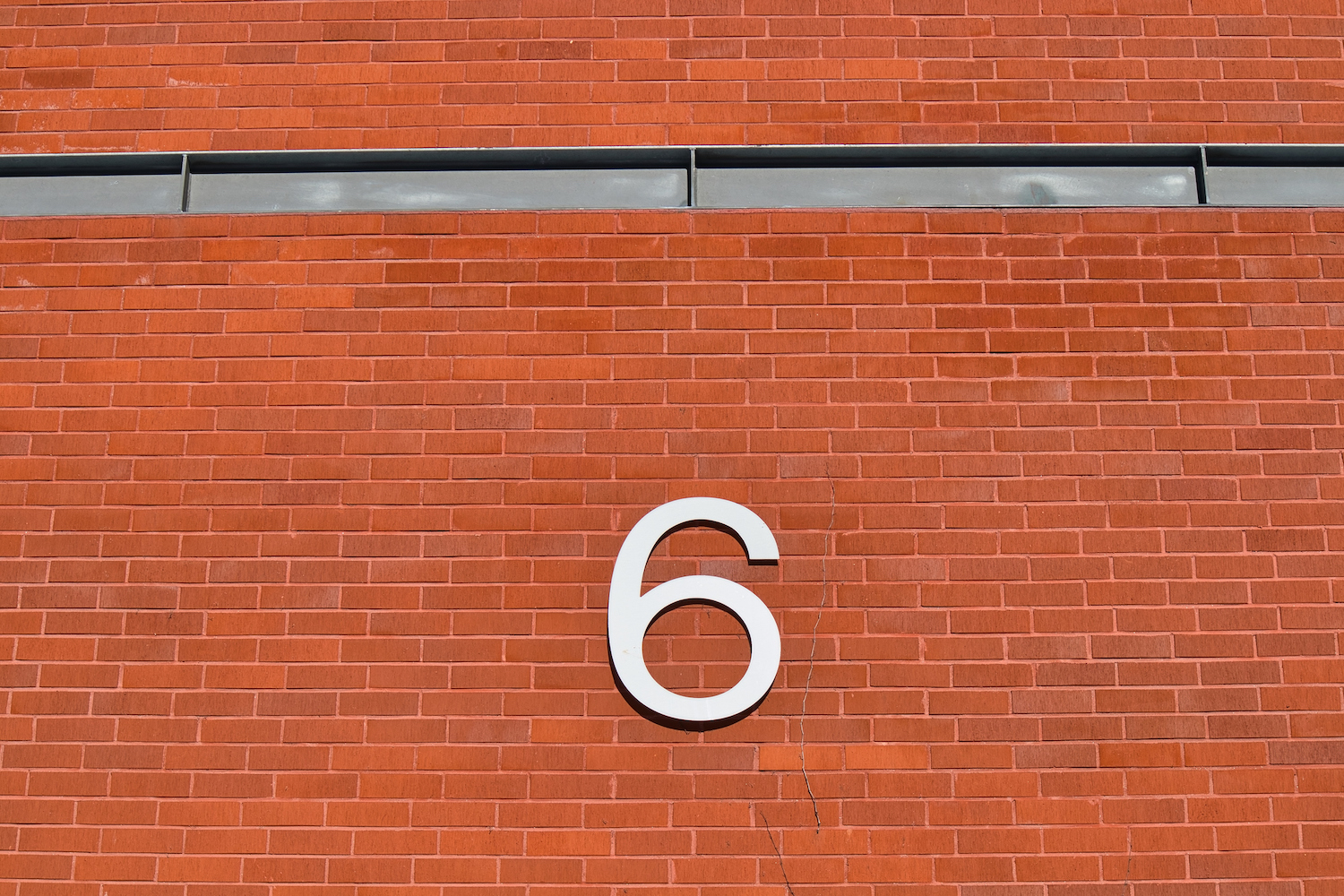 شماره شش روی یک دیوار آجری در فضای باز.  6 چالش رایج پیش روی تیم های امنیت سایبری و نحوه غلبه بر آنها