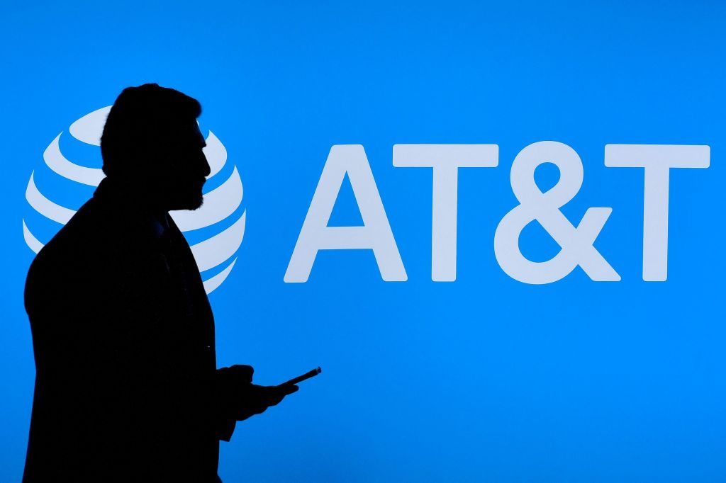 A visitor walks past US multinational telecommunications AT&T logo at the Mobile World Congress