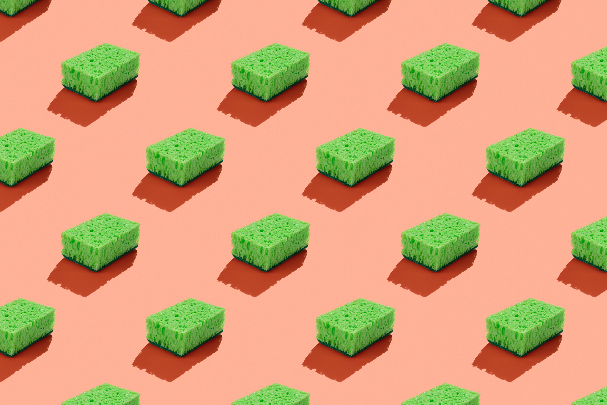 Green sponges on a pink background to symbolize green washing.