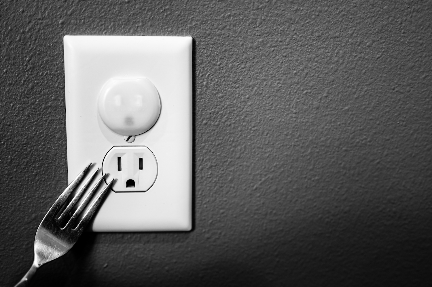 Concept of risks and hazards associated with uncovered electrical outlets with a sharp metal object that can be inserted and cause a shock.