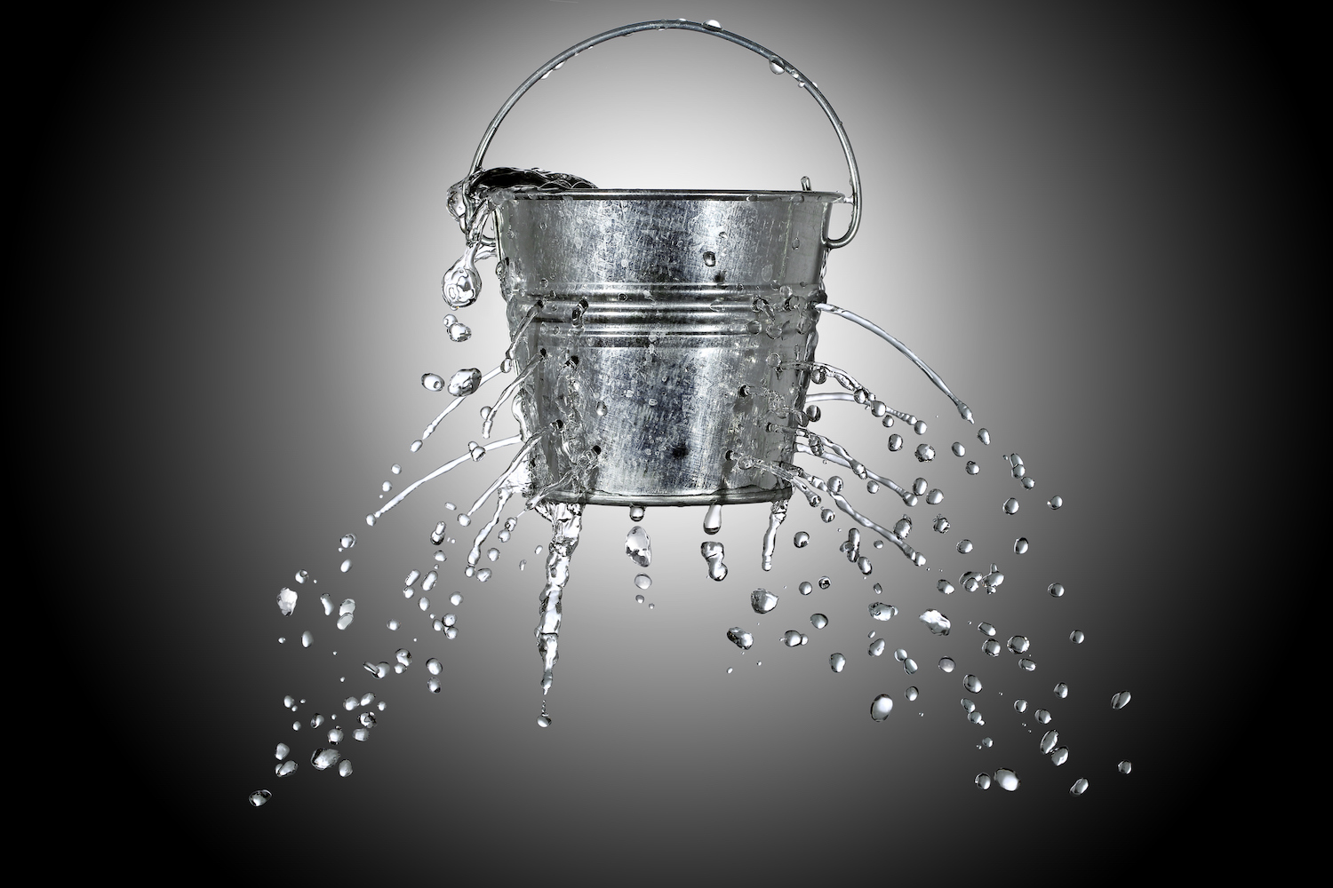 El agua sale de un balde con agujeros