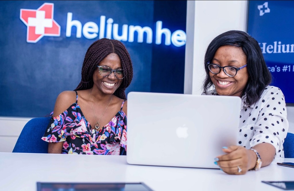 2 women from Helium Health looking at an open laptop