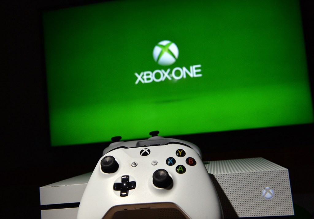an white Xbox controller in front of a television with a green background with the words "XBOX ONE"
