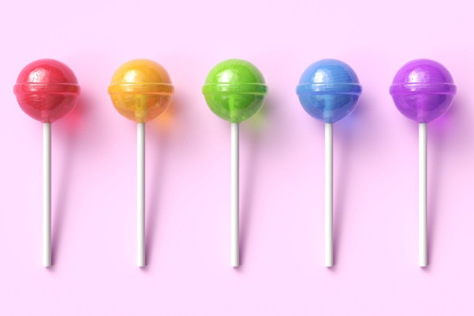 Set of five colorful sweet lollipops on pink pastel background. Round candies on stick. 3d rendering