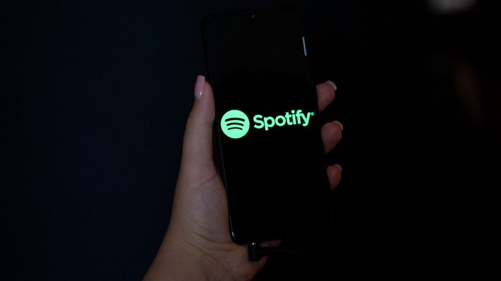 Una mano sosteniendo un teléfono móvil con el logo de Spotify en su pantalla.