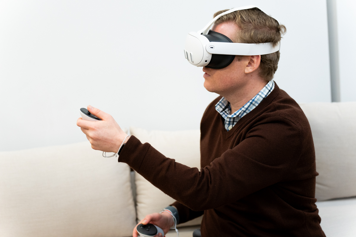 Man wearing the Meta Quest 3 mixed reality headset, holding a controller, viewed from the side