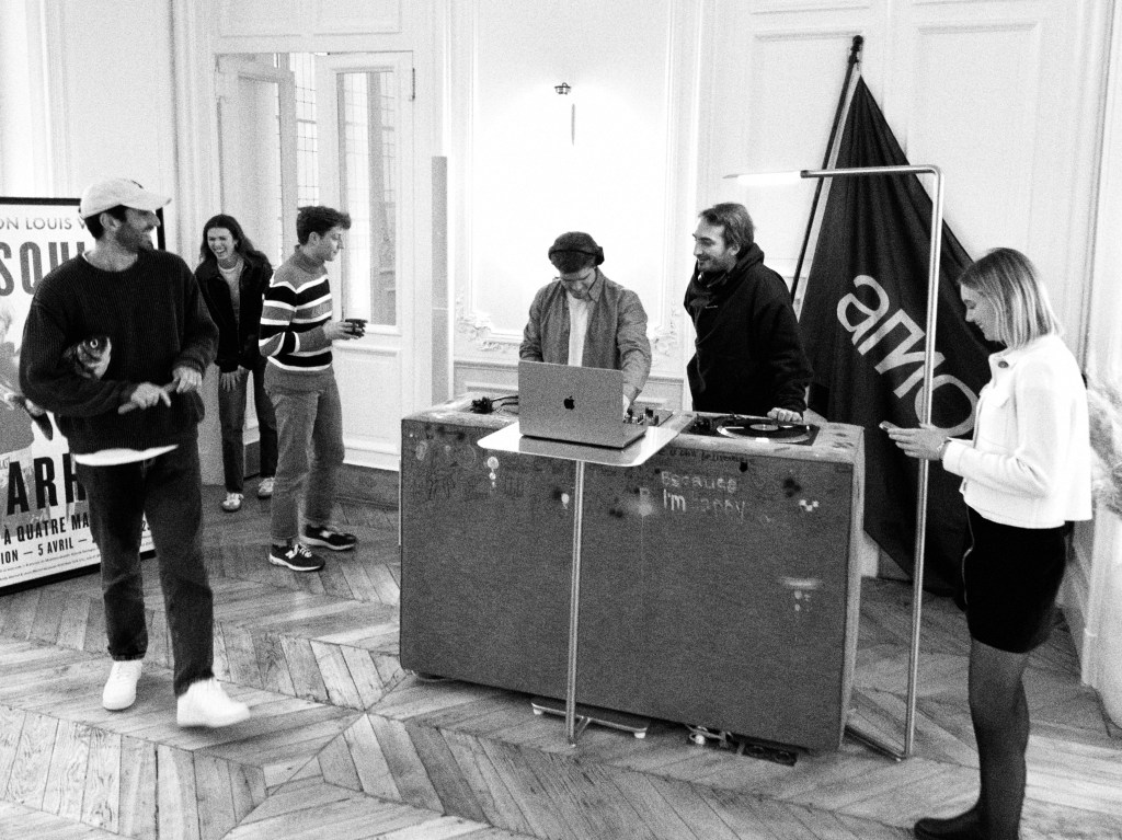Członkowie zespołu Amo w swoim biurze, podczas gdy jeden z nich gra jako DJ