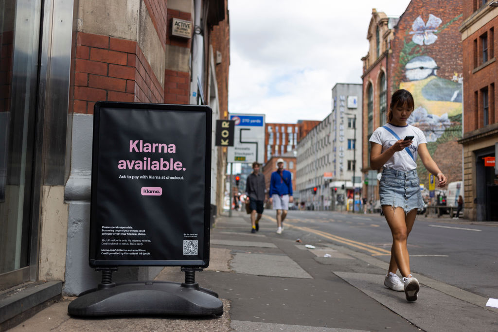 Members of the public pass by a floor advertisement for tech firm Klarna.