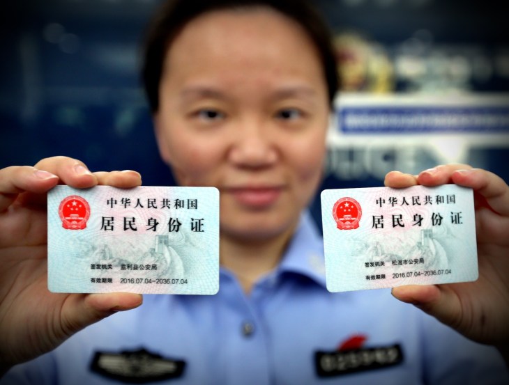 Một sĩ quan cảnh sát xuất trình hai thẻ căn cước sẽ được cấp cho người dân không phải người địa phương tại đồn cảnh sát Chu Gia Kiều ở thành phố Thượng Hải phía đông Trung Quốc