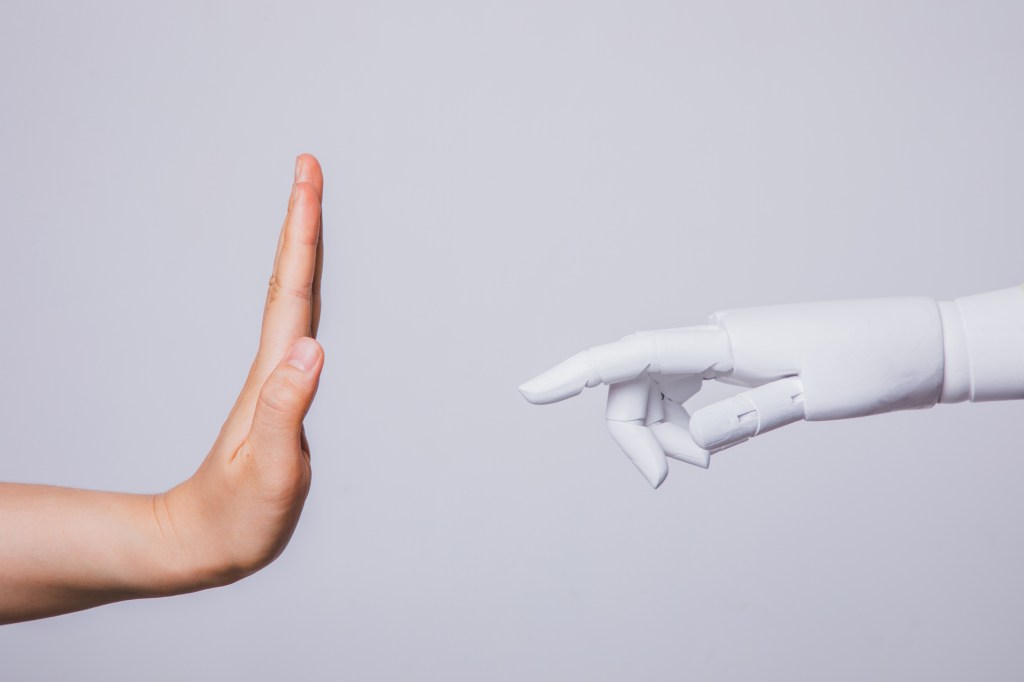 Levantando la mano humana rechazando la mano robótica (Conceptos de rechazo humano a la inteligencia artificial)