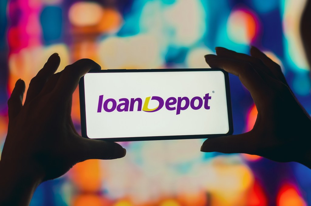 a silhouetted woman holds a smartphone with the LoanDepot logo displayed on the screen.
