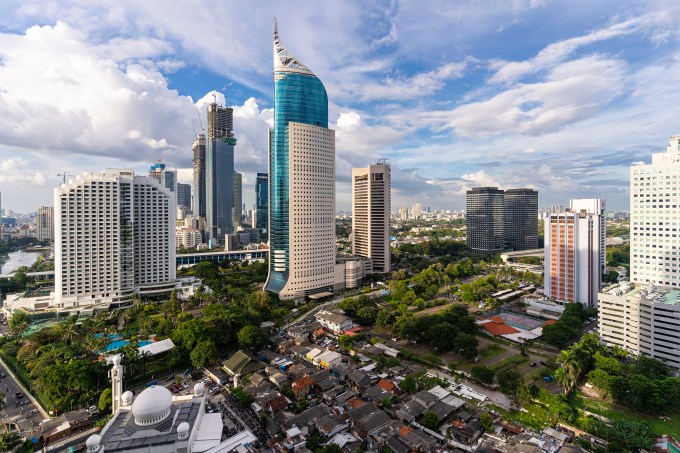Aerial view of Jakarta business district where modern skyscrapers contrasts with low income residential area and mosque in Indonesia capital city in Southeast Asia
