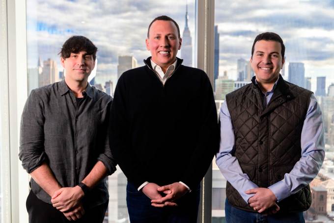 Evan Caron, Philip Krim und Sharo Atmeh posieren vor der Skyline von New York City.